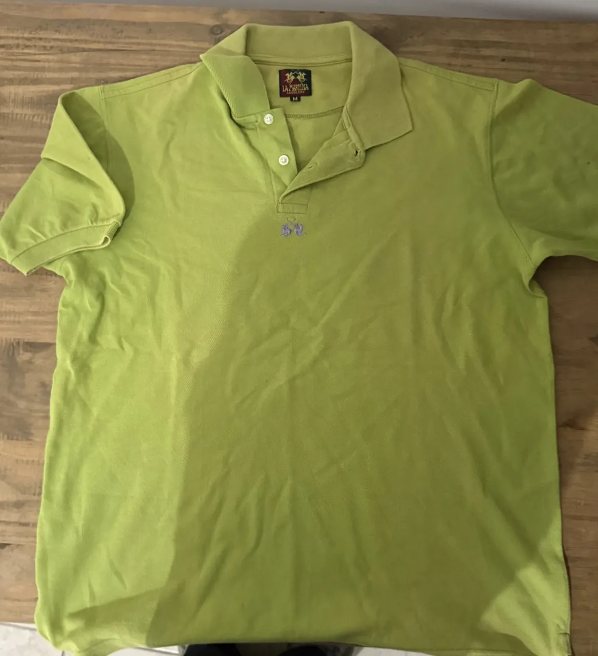 Remera polo color verde lima con dos botones en el cuello y logo bordado en el frente.