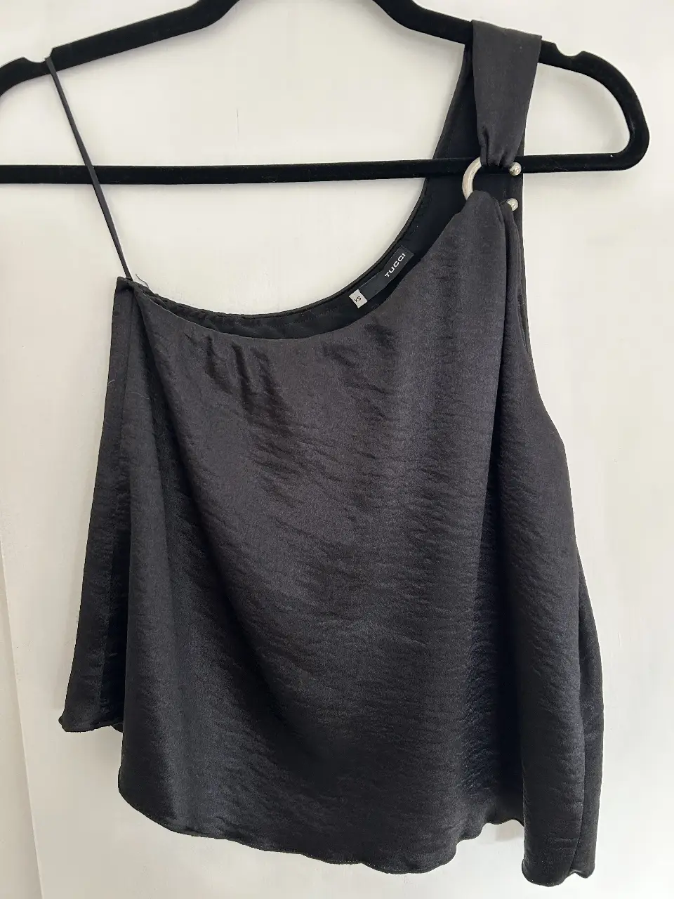 Top negro asimétrico de satén con detalle de avío metálico. Ideal para una salida o evento especial.