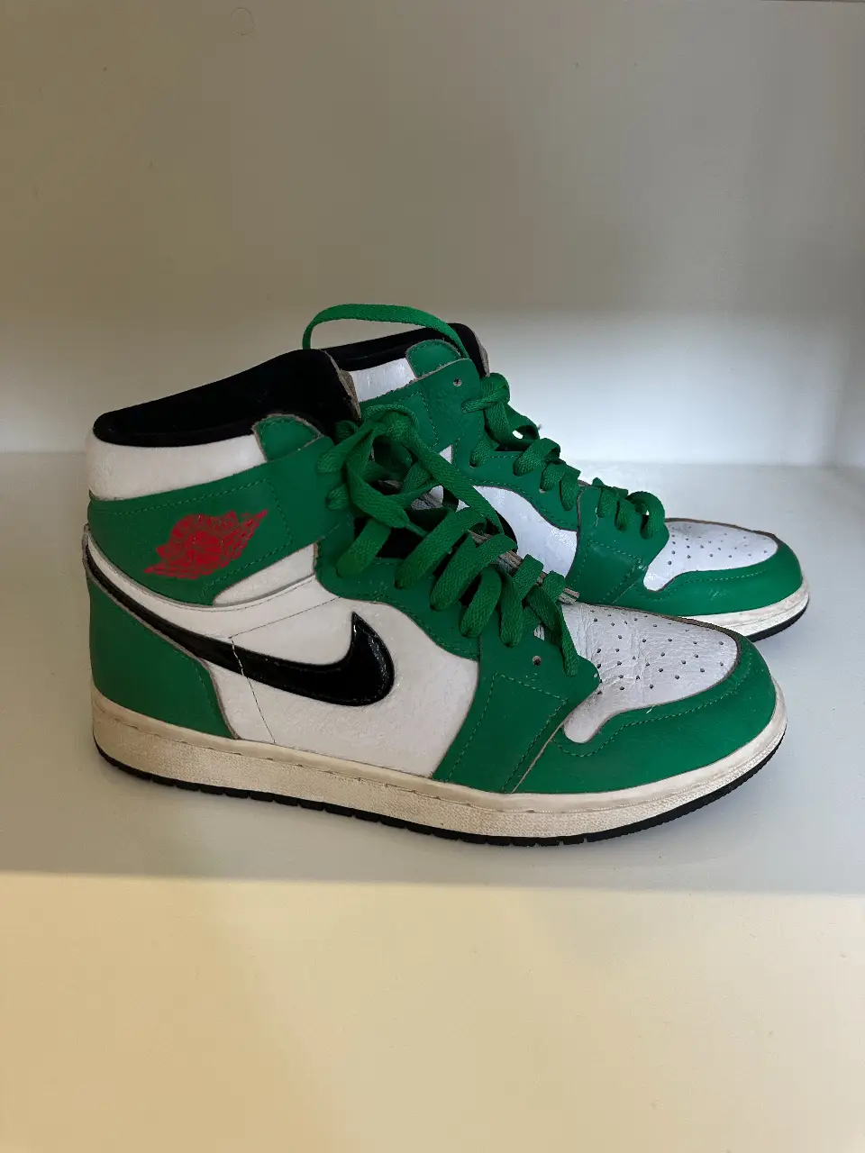 Zapatillas Air Jordan 1 verdes y blancas, un clásico del calzado deportivo con el icónico logo de la marca. Ideales para un look urbano y con estilo.