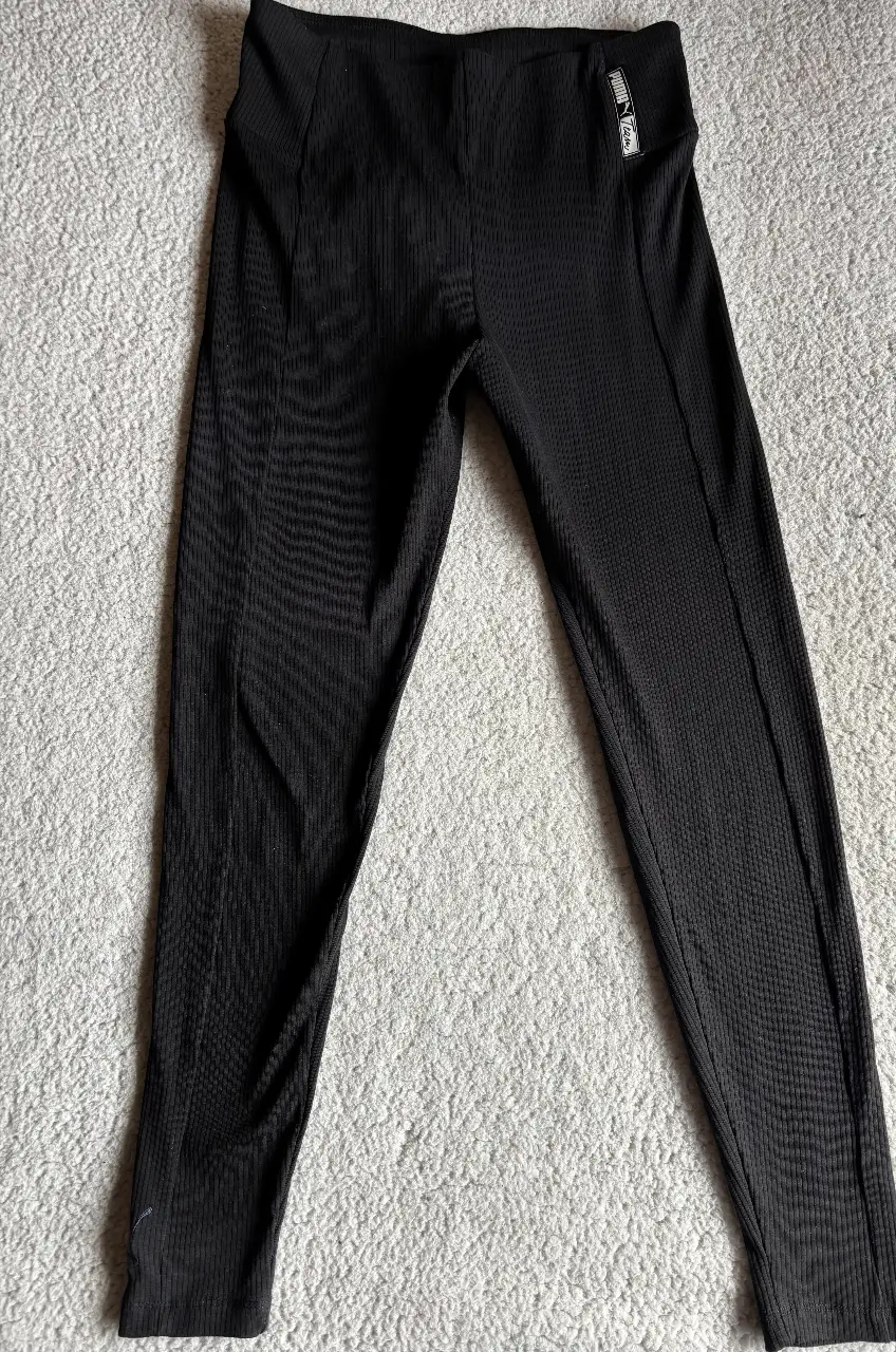 Calzas deportivas negras de la marca Puma, con cintura alta y diseño acanalado. Perfectas para entrenar o para un look casual y cómodo.es un M de Estados Unidos que es más grande .