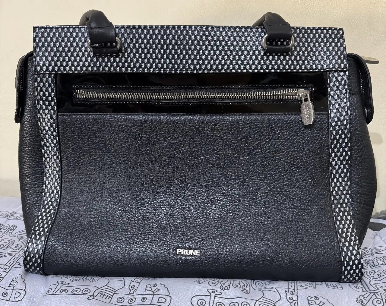 Cartera PRUNE negra con detalles en blanco. Diseño moderno y elegante, ideal para cualquier ocasión. Confeccionada en cuero, ofrece durabilidad y estilo. Perfecta para llevar tus esenciales con sofisticación.