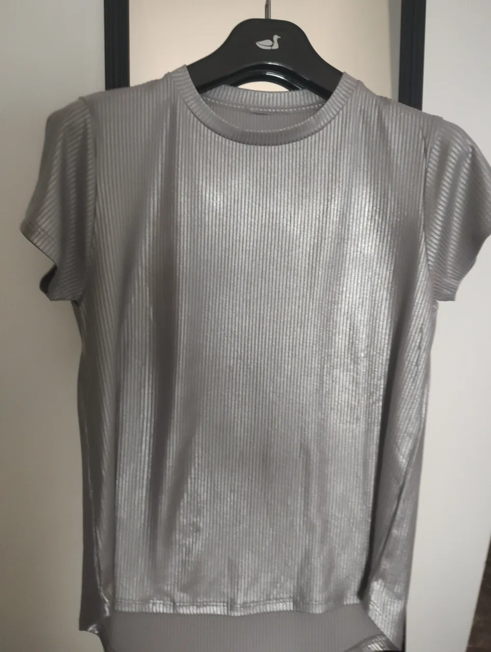 Remera de mujer de manga corta, color gris metalizado, con textura acanalada. Ideal para un look casual y moderno.