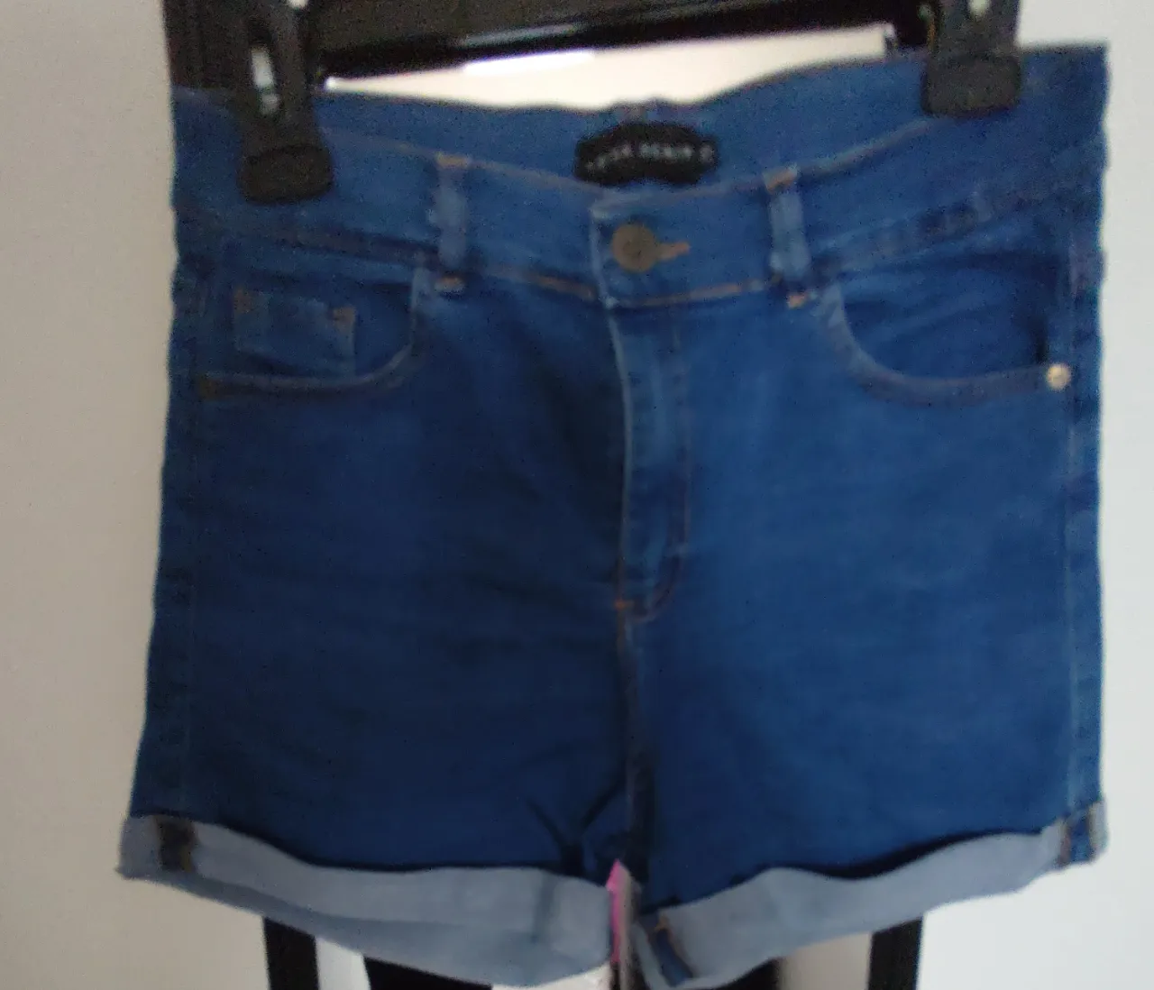 Short de jean azul de mujer, tiro medio, con dobladillo en el borde inferior. Ideal para un look casual y cómodo.