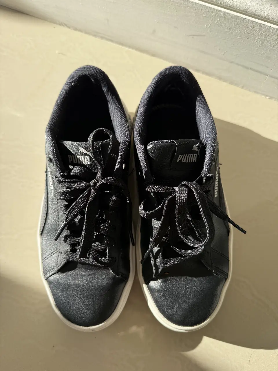 Zapatillas Puma negras de cuero con suela blanca, ideales para un look casual y urbano. Diseño clásico y cómodo, perfectas para el día a día.