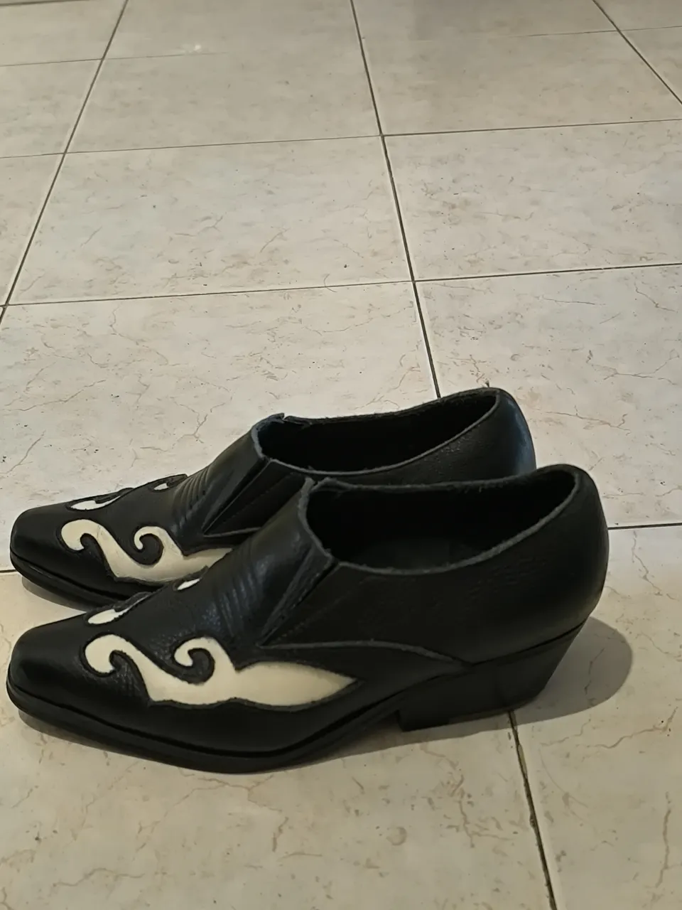 Botas negras con detalles blancos en forma de espiral en la punta y los laterales. Taco bajo.