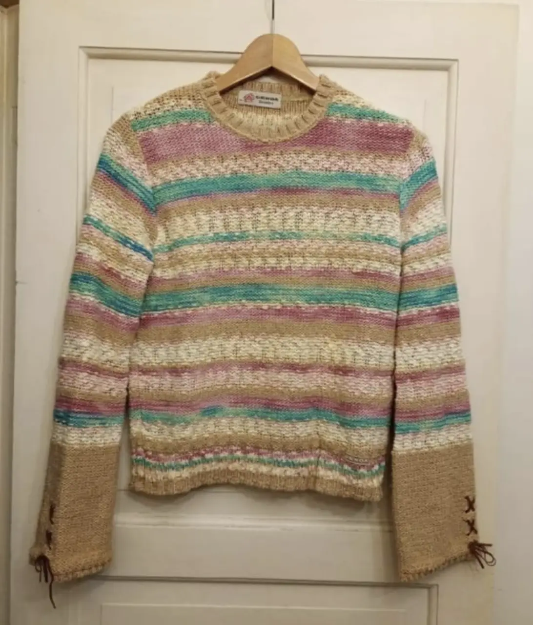Sweater Genoa de lana a rayas horizontales en tonos pastel. Mangas largas con detalle de lazo en los puños. Ideal para un look casual y cómodo.