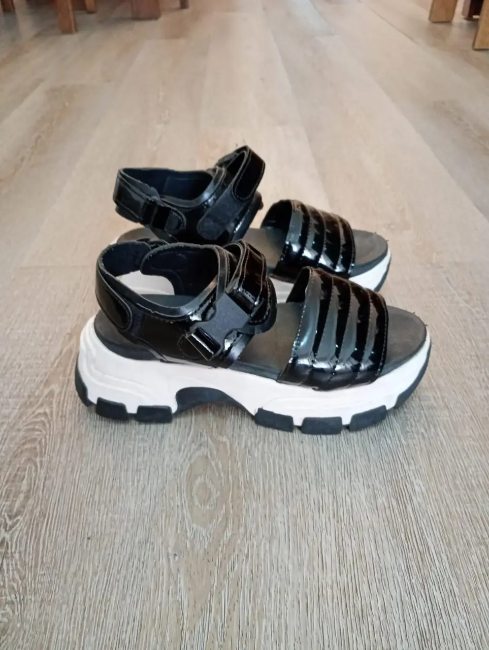 Sandalias de plataforma negras con detalles brillantes y suela blanca. Ideales para un look moderno y cómodo.