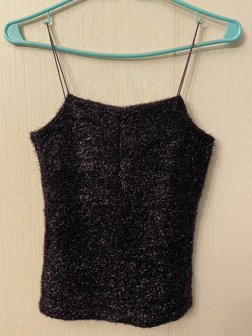 Top negro con tiras finas, ideal para una salida nocturna o evento especial. Confeccionado en un tejido brillante y texturizado, este top añade un toque de glamour a cualquier look. Perfecto para combinar con pantalones de vestir o una falda.