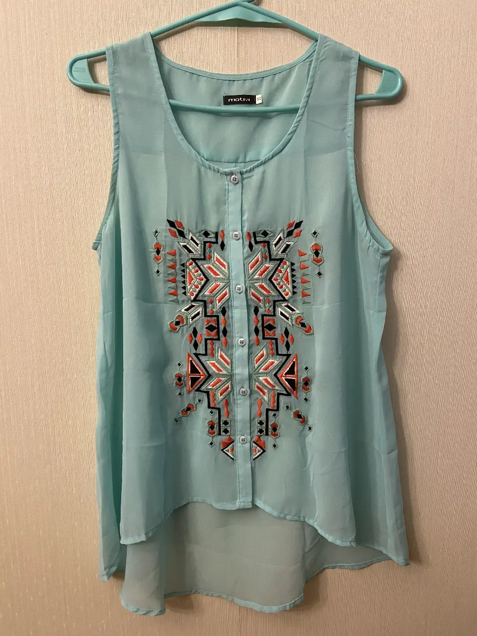 Blusa celeste con bordado geométrico en el frente. Ideal para un look fresco y casual. 