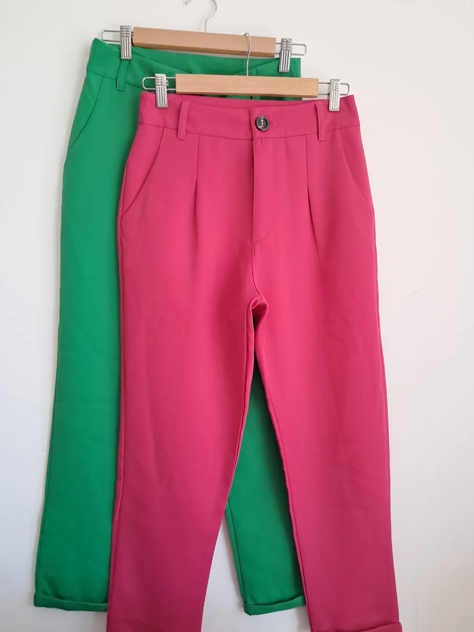 Pantalones sastrero de vestir color verde y fucsia. Tienen pinzas en la parte delantera, bolsillos laterales y un botón en la cintura.