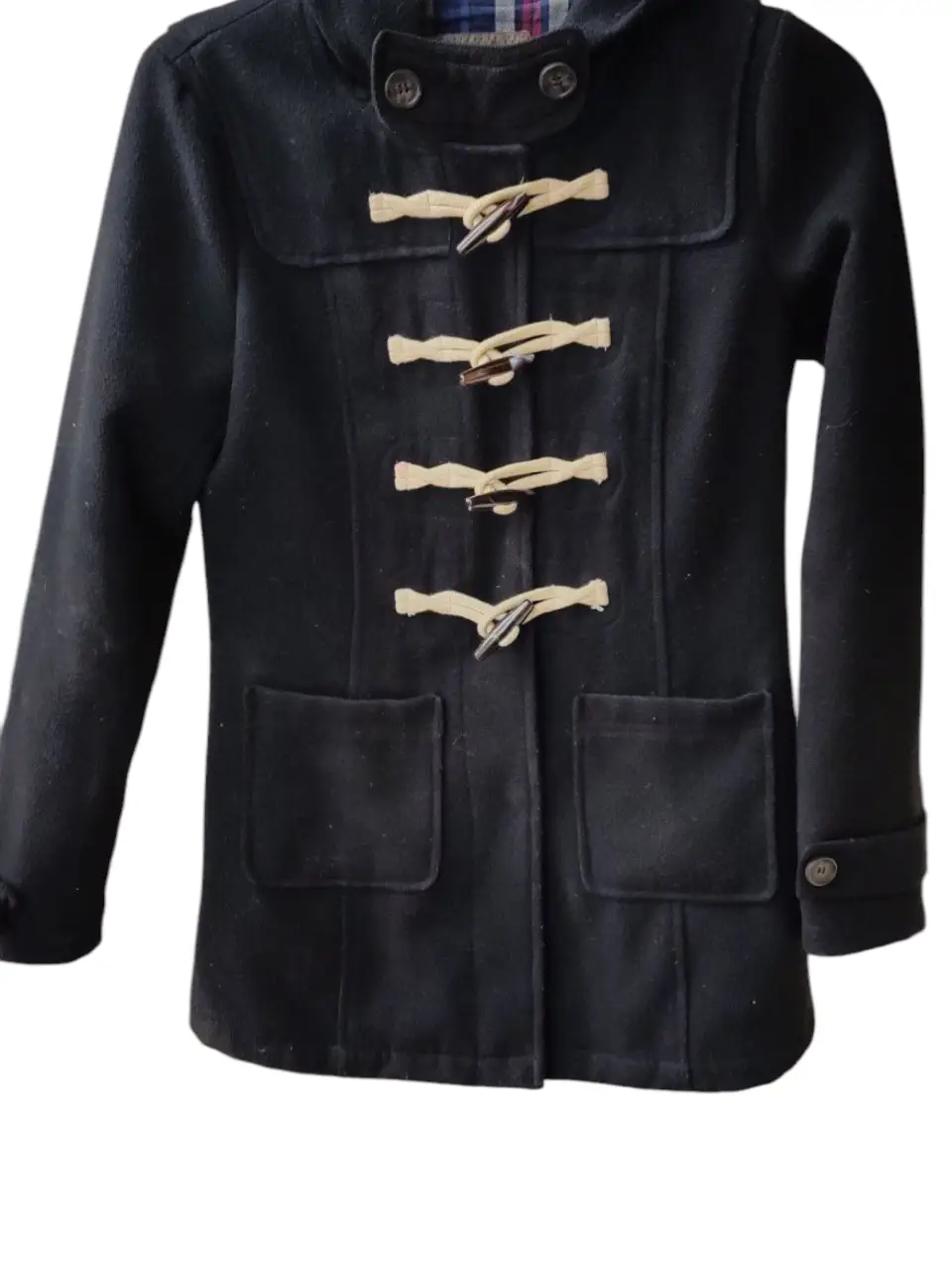 Montgomery negro con capucha y botones de madera. Posee forro interior a cuadros.