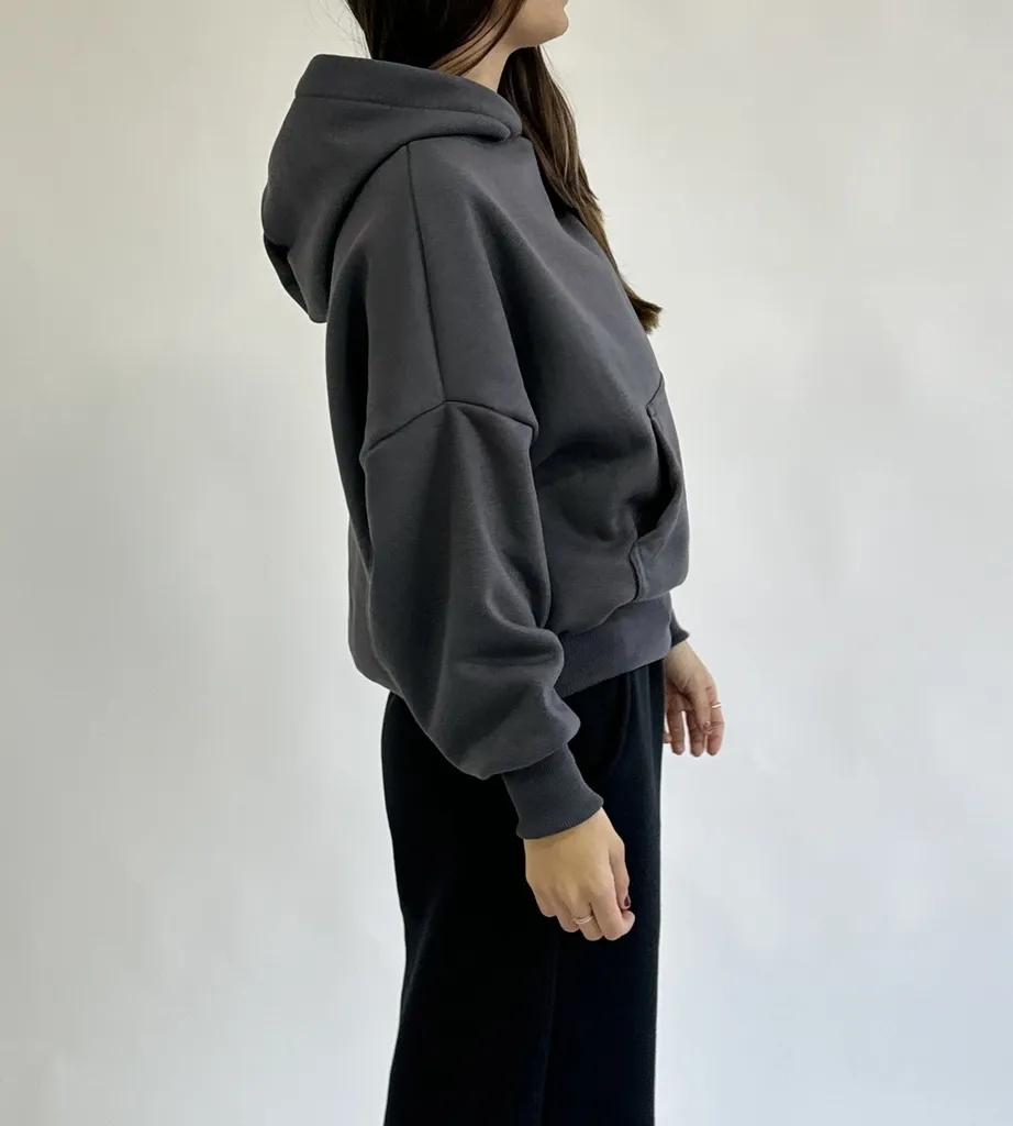 Buzo boxy de mujer frizado, de color gris oscuro. Con capucha y bolsillo frontal. Ideal para un look casual y cómodo.