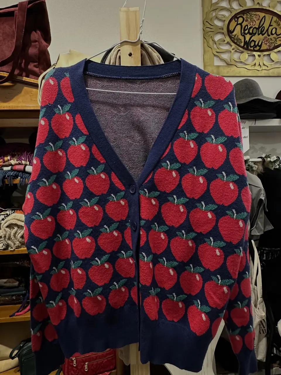 Cardigan de mujer con estampado de manzanas rojas sobre fondo azul marino. Diseño con cuello en V y cierre con botones. Ideal para un look casual y con estilo.