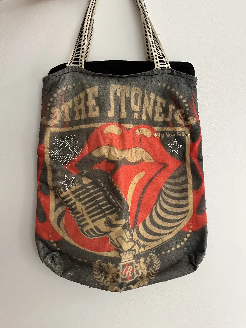 Bolso tote de tela con estampado de la banda The Rolling Stones. Diseño vintage con la icónica lengua y micrófono. Ideal para llevar tus cosas con estilo rockero.