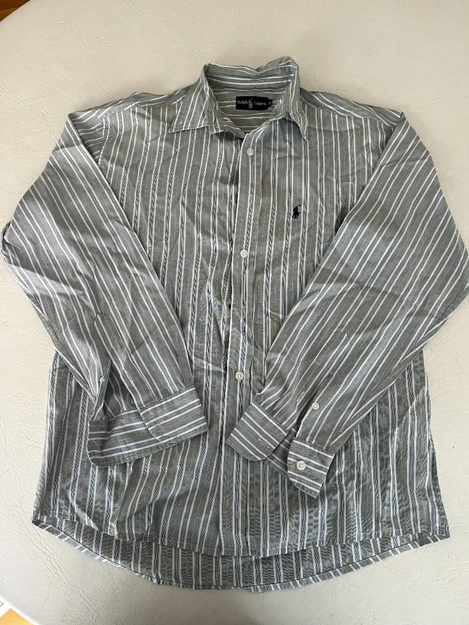 Camisa a rayas gris y blanca de hombre, manga larga. Marca Ralph Lauren talle M, con logo de la marca en el pecho. Ideal para un look casual y versátil.