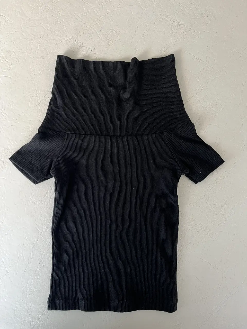 Remera negra de cuello alto y mangas cortas, que también puede usarse como se muestra en la última foto DE EJEMPLO (la última foto no es mi remera).          Confeccionada en tejido de punto acanalado, ofrece un ajuste ceñido y cómodo. Perfecta para combinar con jeans, faldas o pantalones de vestir.