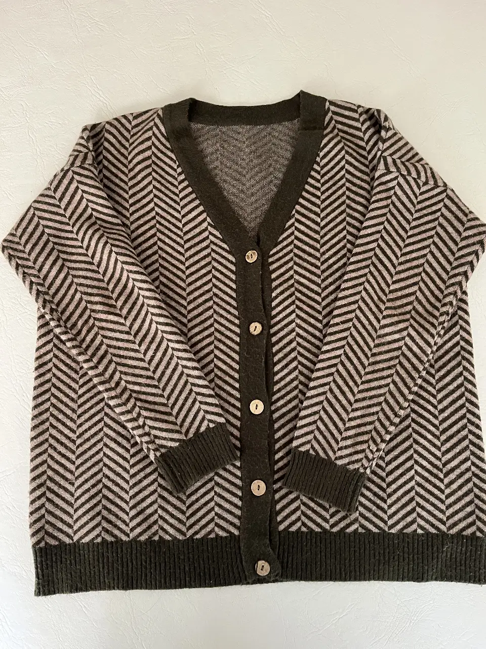 Cardigan de punto con diseño de espiga en tonos marrón y gris. Cuello en V, cierre con botones y puños ajustados. Ideal para un look casual y abrigado.