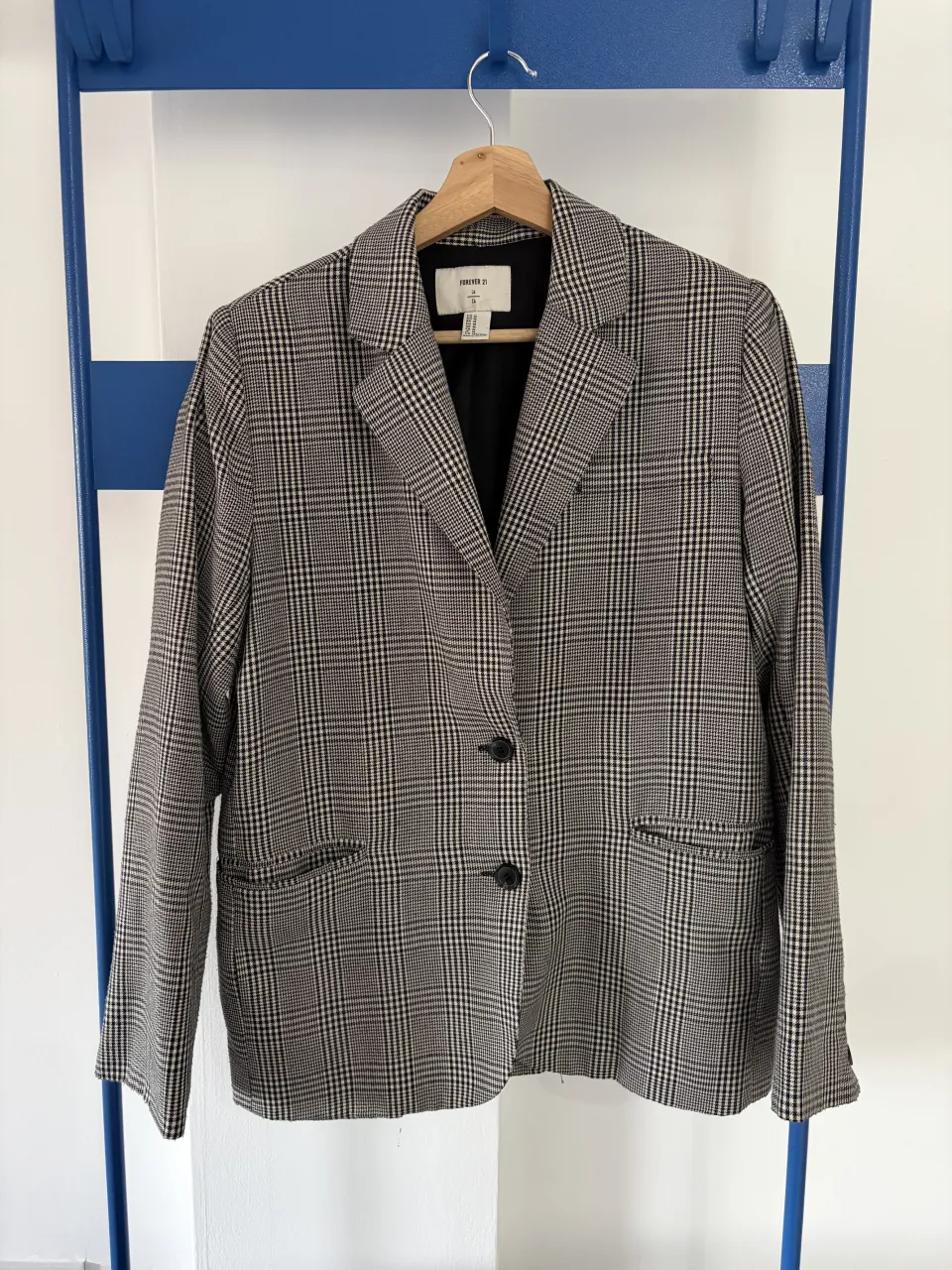 Blazer a cuadros de corte clásico, ideal para un look elegante y sofisticado. Perfecto para la oficina o para elevar un outfit casual.