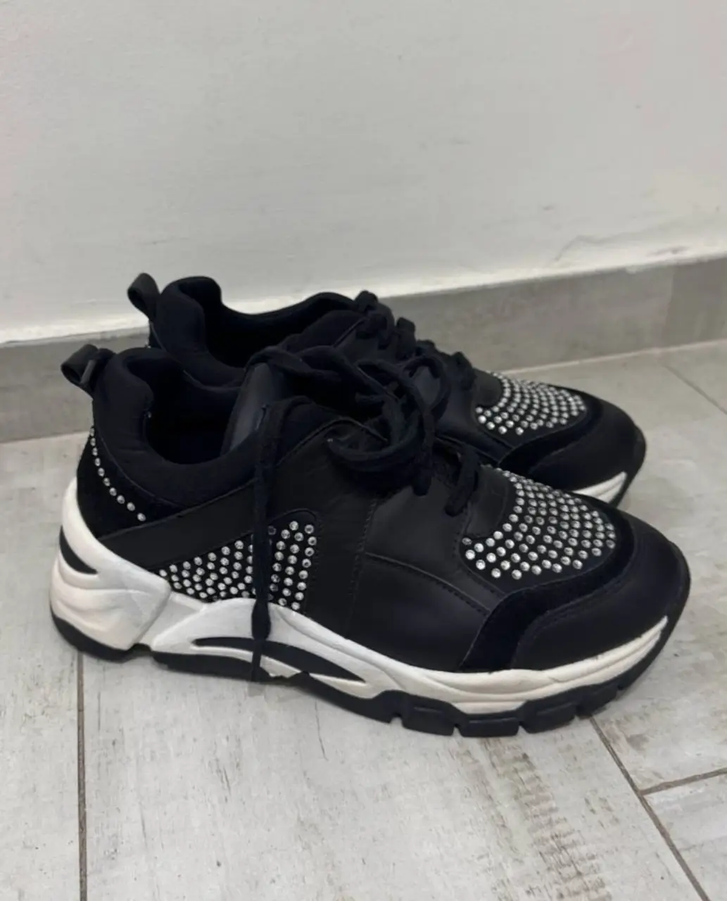 Zapatillas negras con detalles de strass y suela blanca. Marca Sarkany.