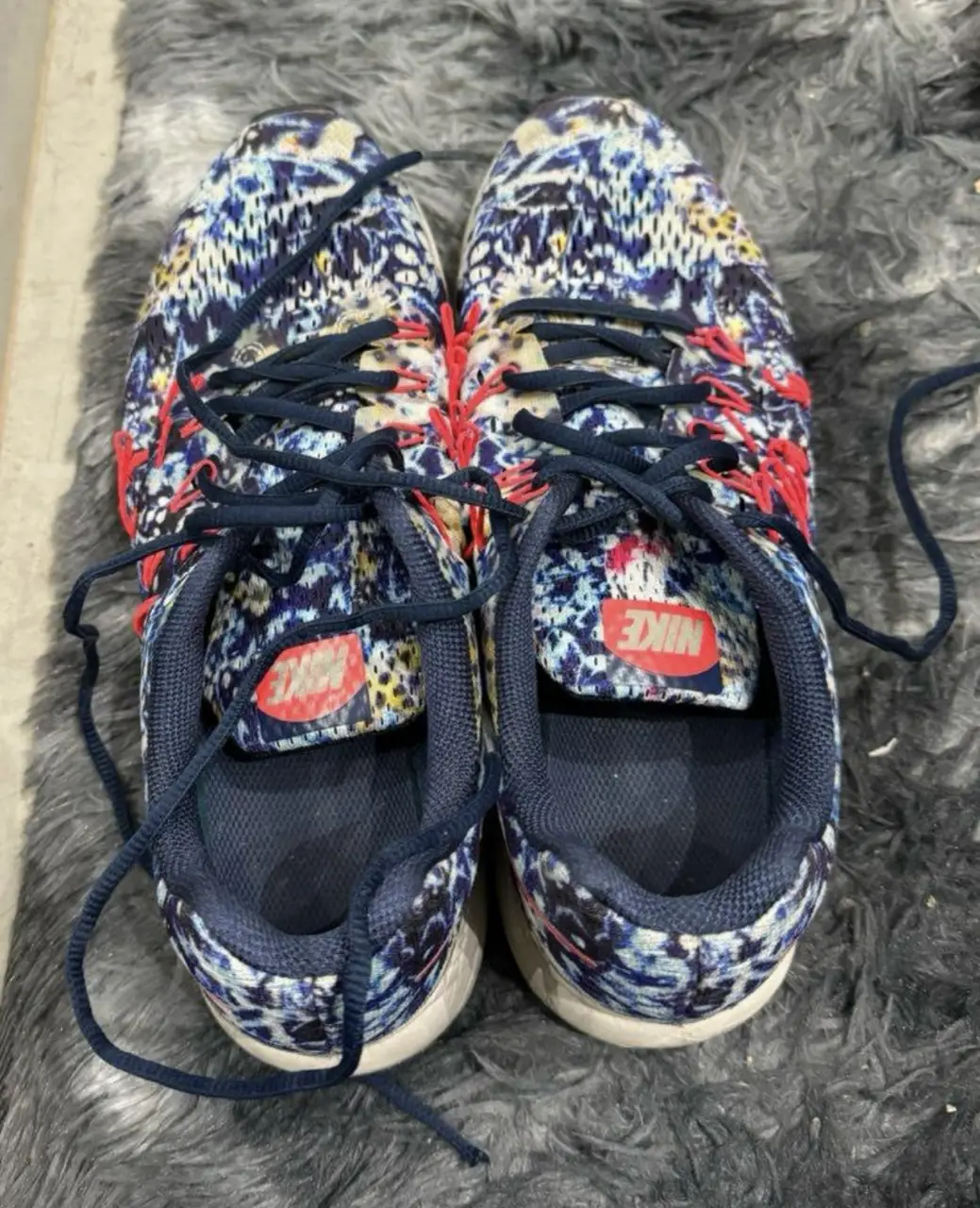 Zapatillas Nike con estampado floral en tonos azules y rojos. Ideales para running o uso diario.