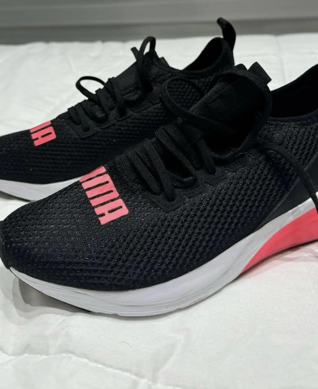 Zapatillas Puma negras con detalles en rosa, ideales para running y uso diario. Diseño moderno y cómodo.