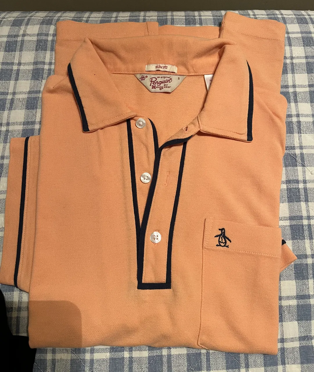 Remera polo de hombre, color durazno con detalles en azul marino. Diseño clásico con cuello y bolsillo en el pecho. Ideal para un look casual y elegante.