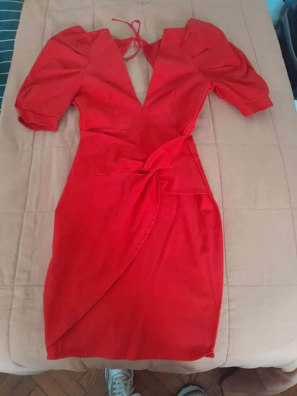 Vestido mini rojo con escote en V y mangas cortas abullonadas. Detalle de nudo en la cintura y espalda descubierta con lazo. Ideal para una fiesta o salida.
