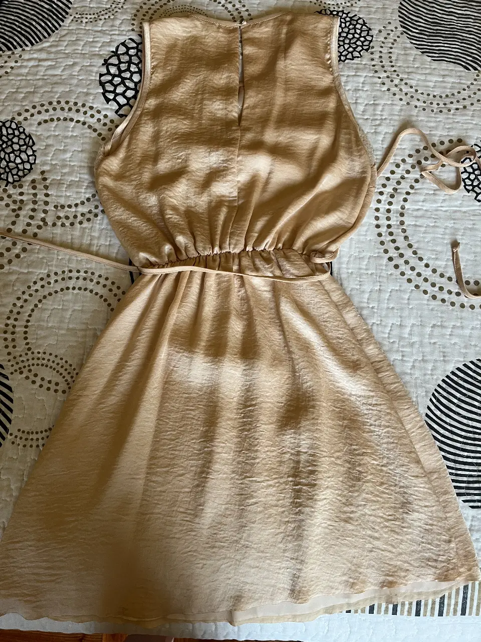 Vestido mini de fiesta en tono dorado, con detalles de pedrería en la parte superior y cintura entallada. Ideal para eventos especiales.