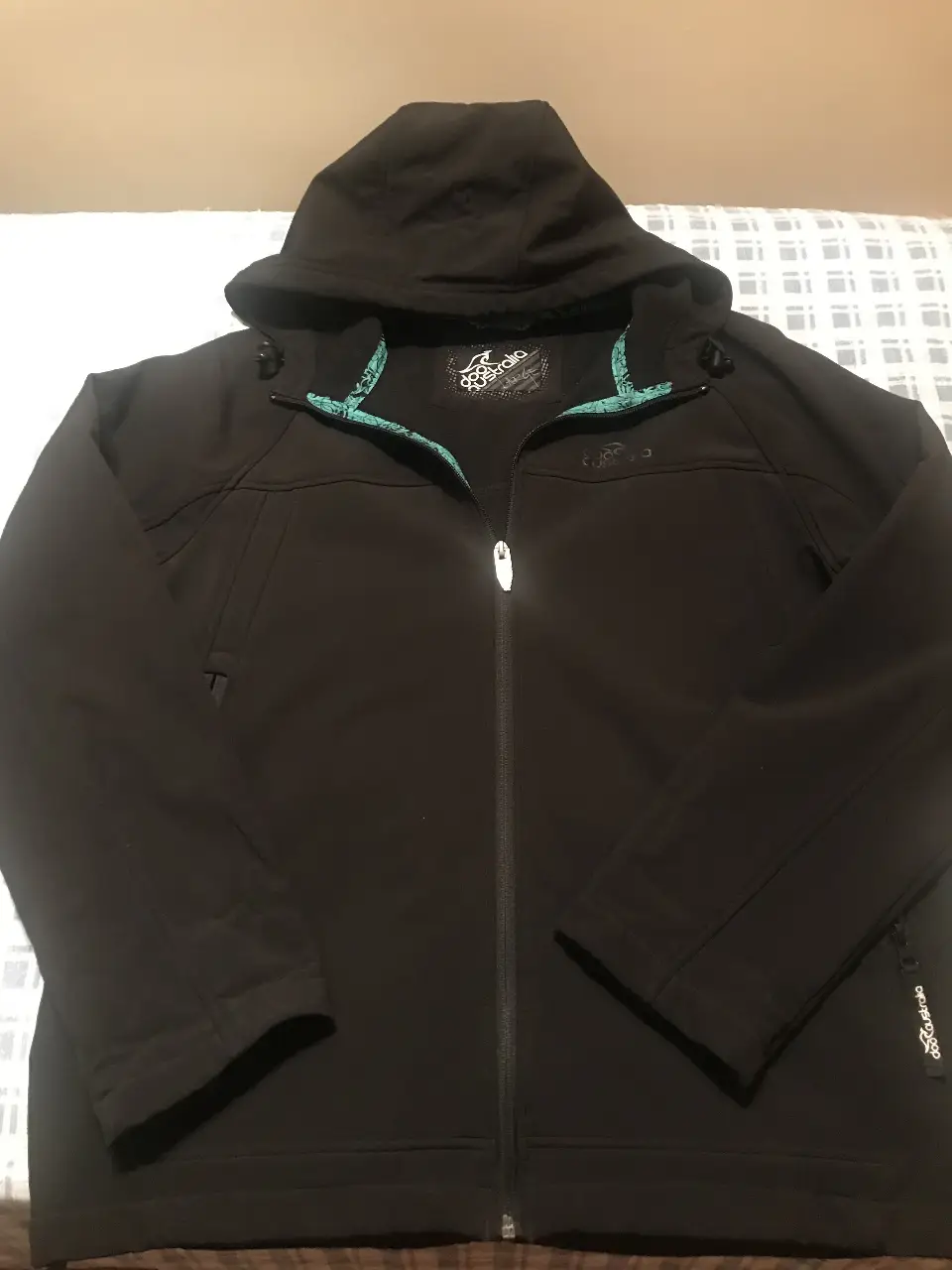 Campera deportiva negra con capucha, cierre frontal y detalles en turquesa en el interior. Ideal para actividades al aire libre y uso casual.