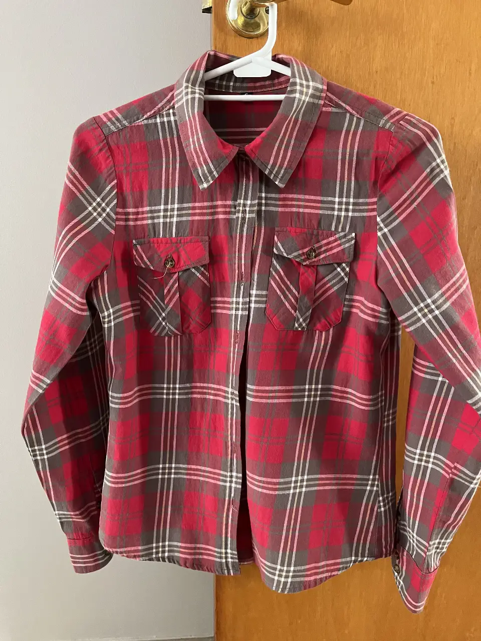 Camisa a cuadros roja y gris, de manga larga, con dos bolsillos delanteros y cuello clásico. Ideal para un look casual y versátil.