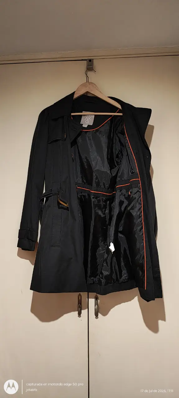 Trench negro clásico, ideal para el invierno. Posee cinturón para ajustar la cintura y un diseño elegante. Perfecto para un look formal o casual.