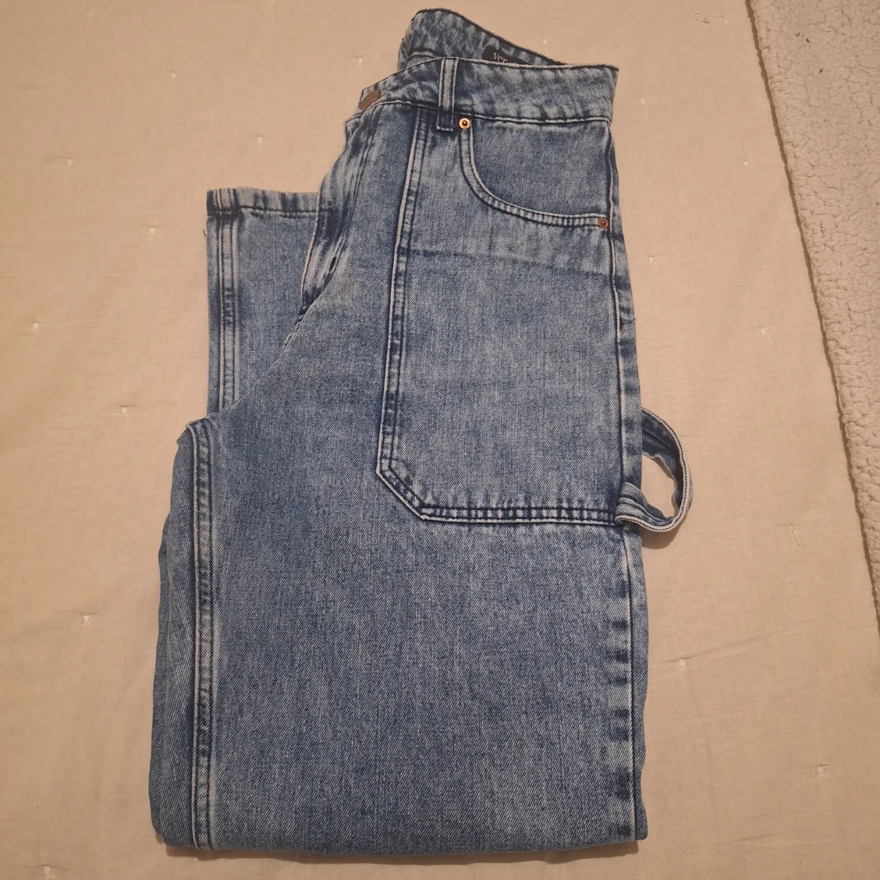 Jeans rectos de mujer, tiro alto, con bolsillos delanteros y traseros. Diseño utilitario con detalles de costura y etiqueta de la marca en la parte trasera.