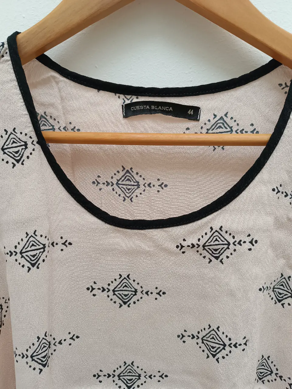 Blusa sin mangas con estampado geométrico en tonos neutros. Cuello redondo con borde negro y detalle de la misma tonalidad en la parte inferior. Ideal para un look casual y fresco.