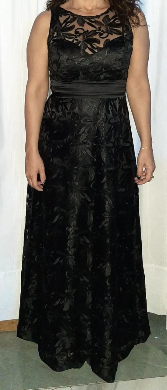 Vestido largo de fiesta negro con detalles florales en relieve. Corte entallado con cintura marcada y escote redondo. Ideal para eventos formales.