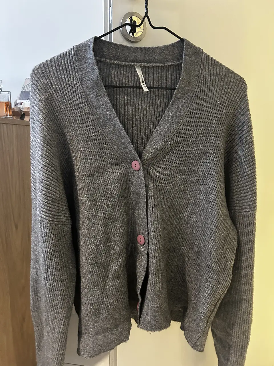 Cardigan de punto gris con botones rosas. 