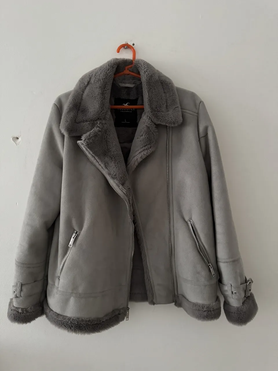 Campera de gamuza, color gris, con forro de piel sintética. Marca Hollister, talle L. Ideal para el invierno.