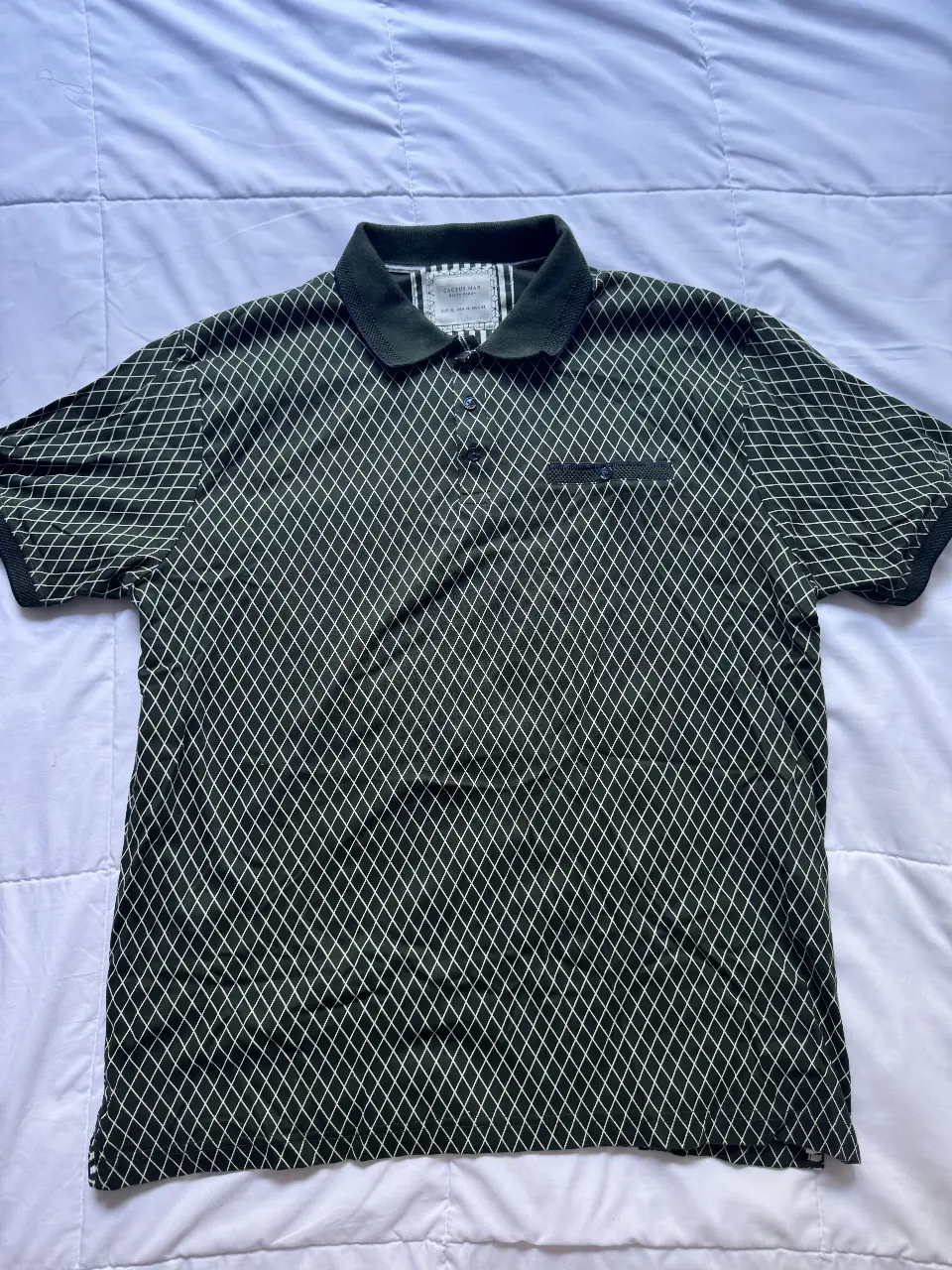 Remera polo para hombre, de color verde oscuro con estampado de rombos blancos. Cuello y mangas en tono verde oscuro. Marca Cactus Man Ricky Singh. Talle XL.