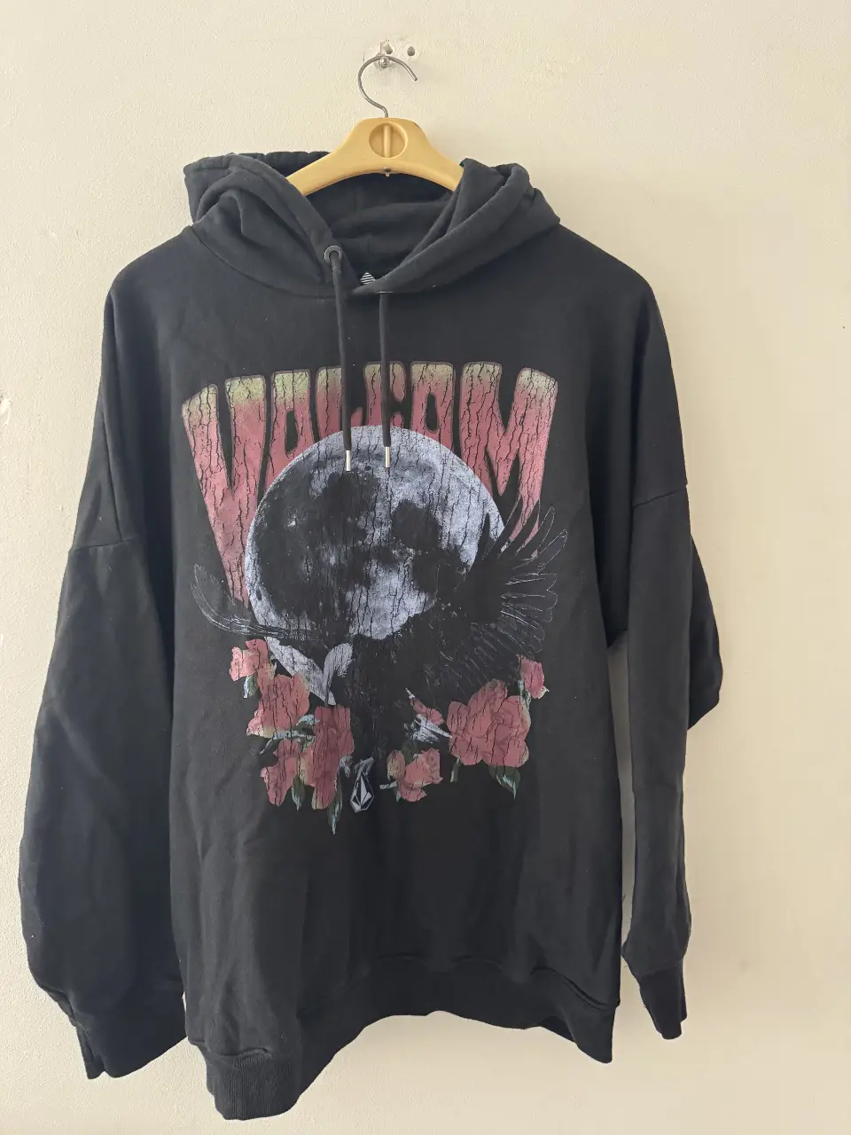 Buzo canguro negro de hombre con estampado de un águila frente a la luna y flores rojas. Marca Volcom. Talle M.