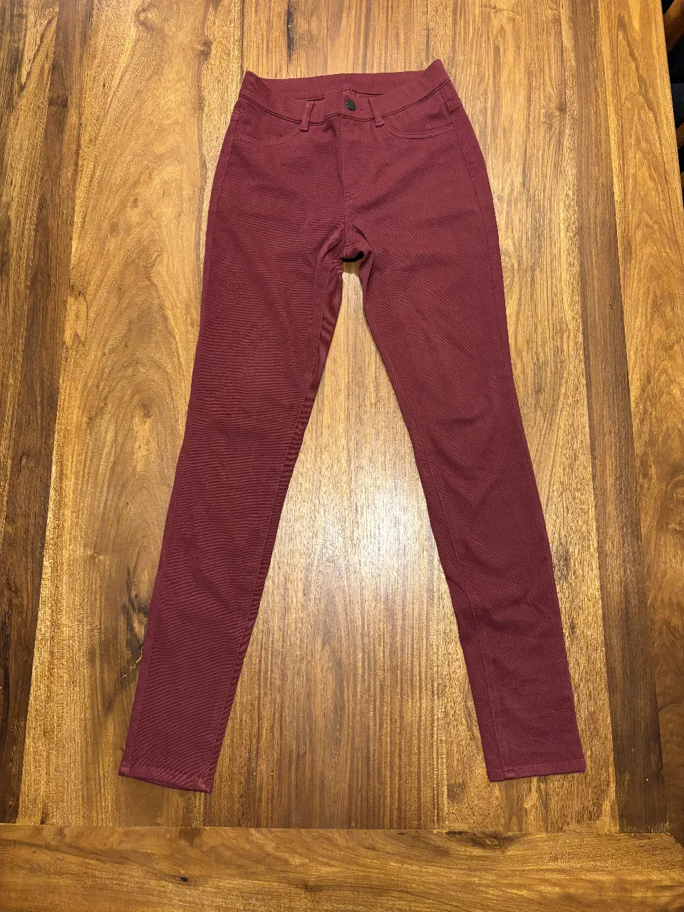 Pantalón tipo jean de mujer (calzas) color borgoña, de la marca Uniqlo, talle XS. Confeccionado en algodón, poliéster y spandex. Ideal para un look casual y cómodo.