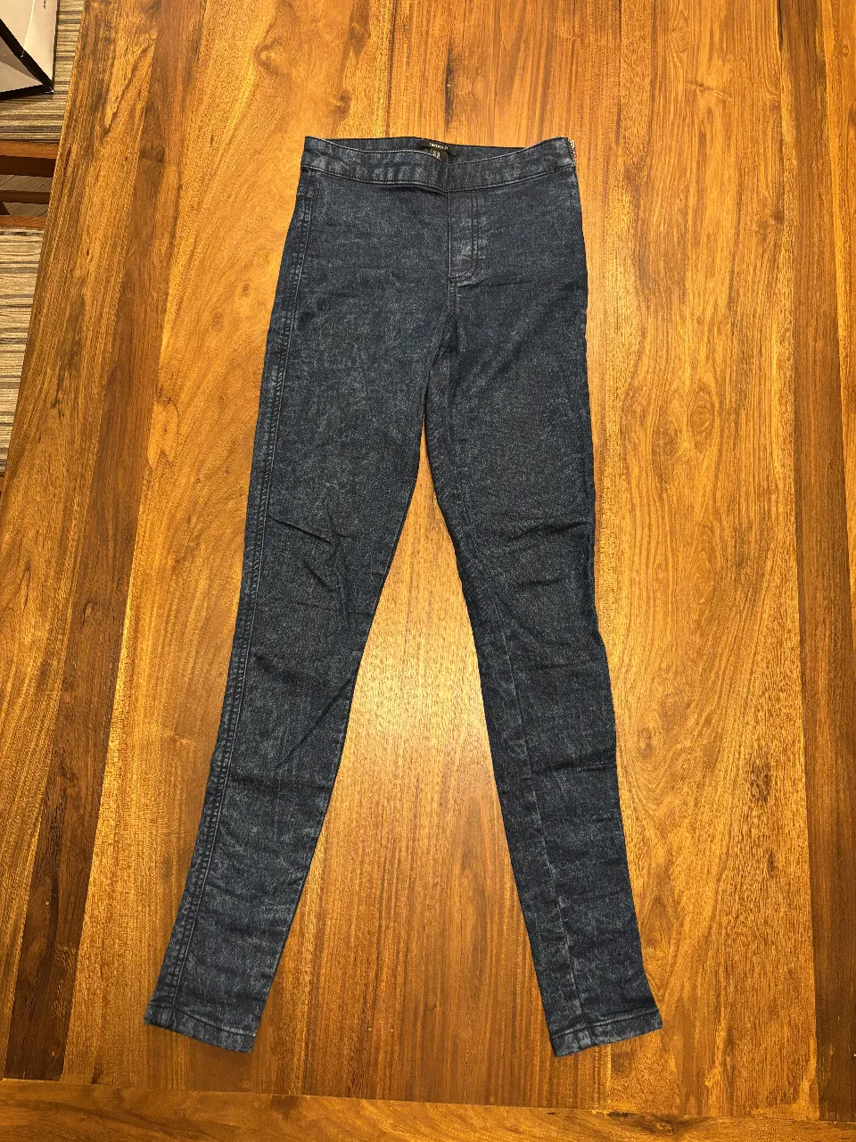 Pantalón chupín de jean elastizado azul oscuro, con efecto gastado. Marca Forever 21, talle XS.