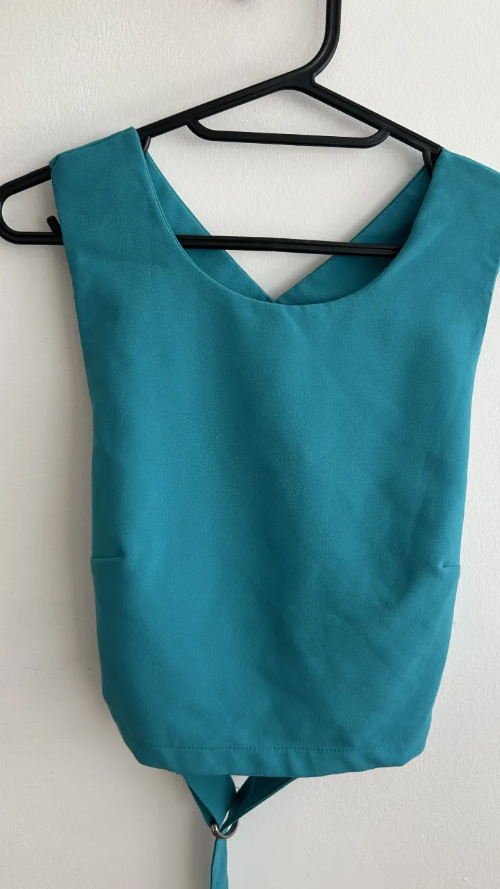 Top color turquesa con breteles cruzados en la espalda y detalle de argolla 