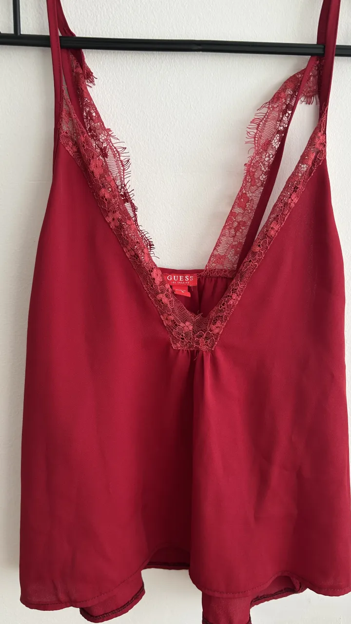 Top de seda color rojo con detalles de encaje en el escote y breteles. Escote en V pronunciado.