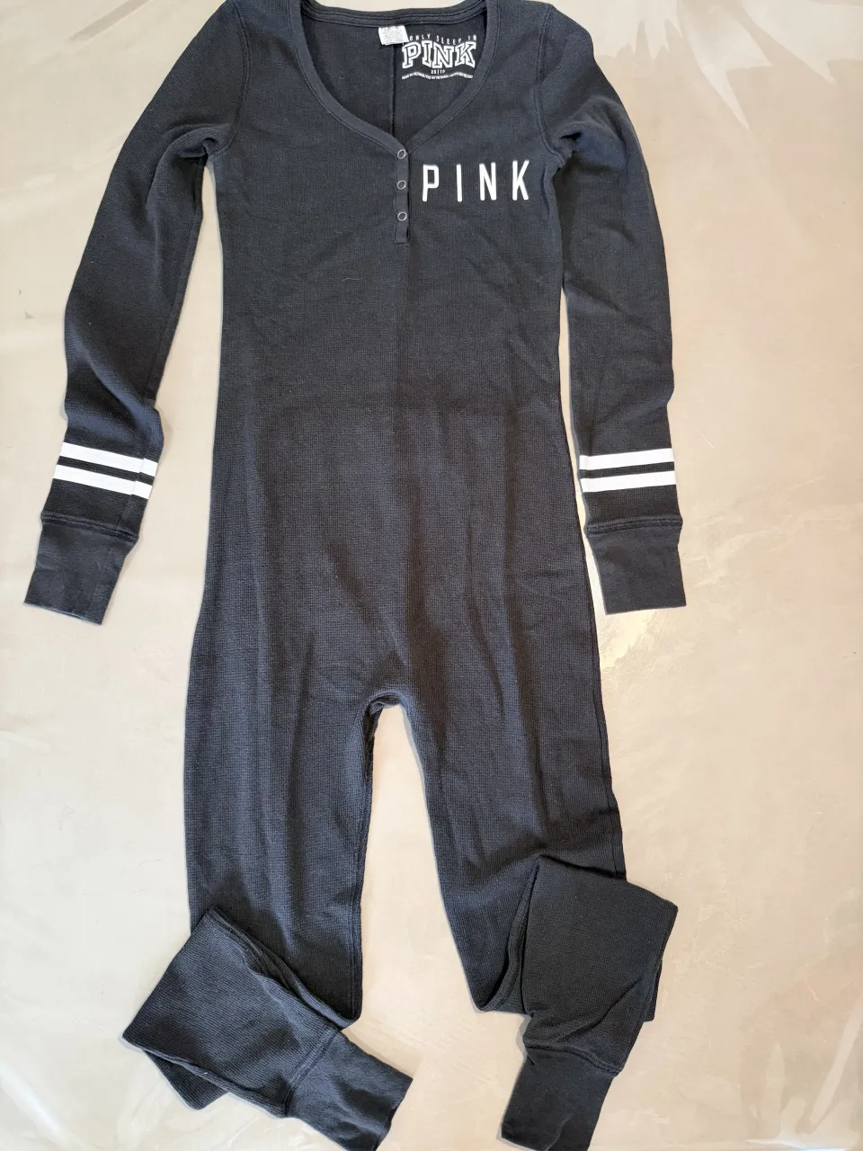 Enterito de pijama súper cómodo y canchero de la marca Pink. Ideal para estar en casa con estilo. Tiene un diseño divertido con la frase "Party All Day Party All Night" en la espalda y detalles de rayas en las mangas. Perfecto para relajarse o para una pijamada.