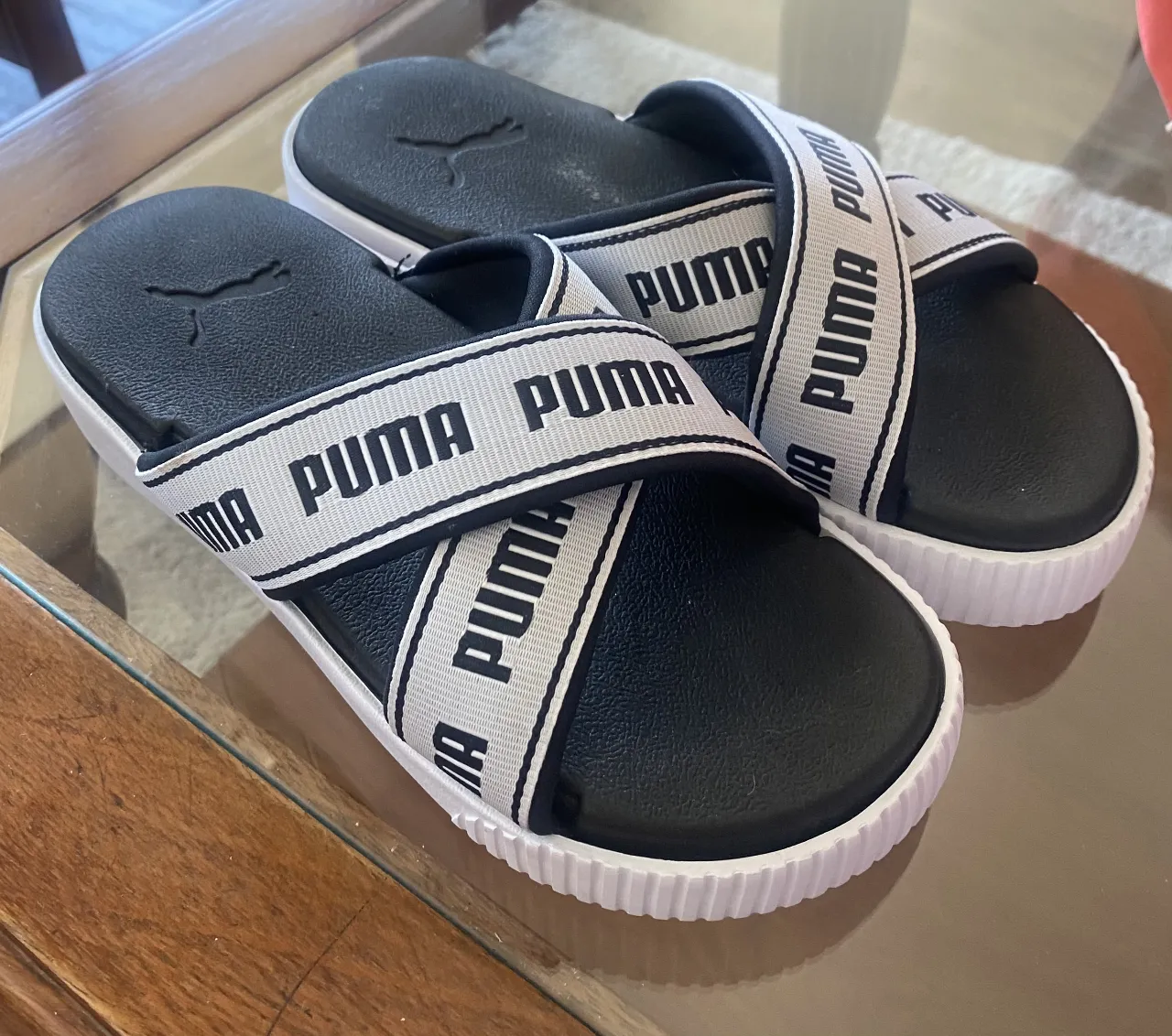 Sandalias PUMA para mujer, con diseño cruzado y logo de la marca en la tira. Ideales para un look casual y cómodo.