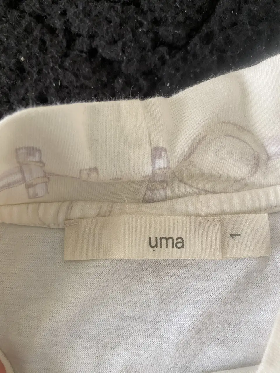 Remera de cuello alto de la marca Uma, con estampado sutil. Ideal para un look casual y cómodo.