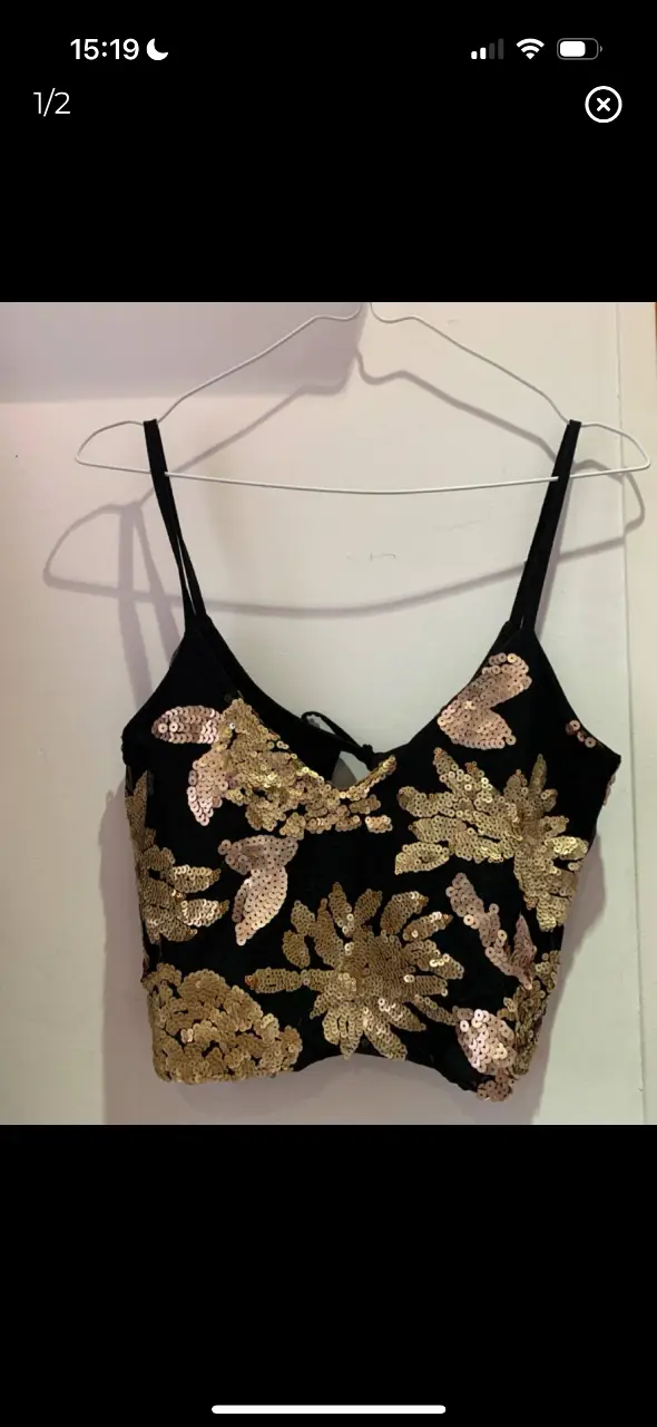 Top negro con lentejuelas doradas en forma de flores. Ideal para fiestas y eventos especiales. Diseño con tirantes finos y espalda descubierta.