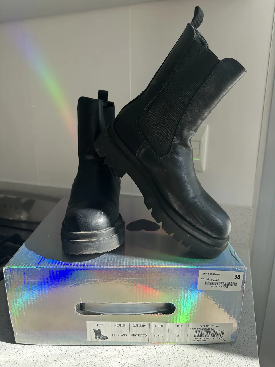 Botas negras de cuero con elástico a los costados y suela track. Cierre con tiras en la parte trasera.