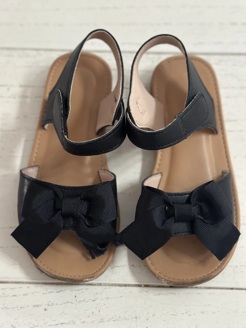 Sandalias negras con lazo en la punta y tira en el tobillo.