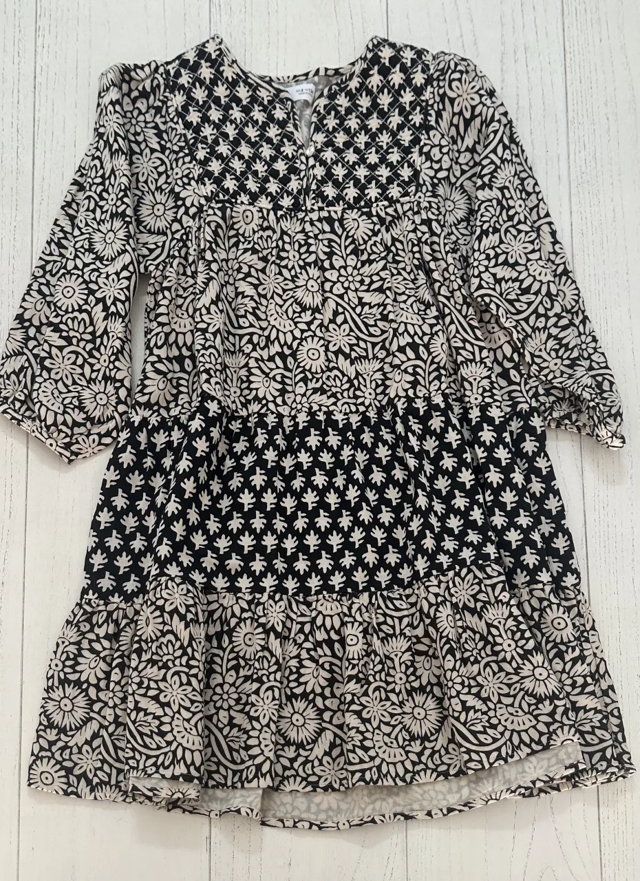 Vestido estampado con mangas 3/4 y volados en la falda. Posee cuello en V con detalle de botones.