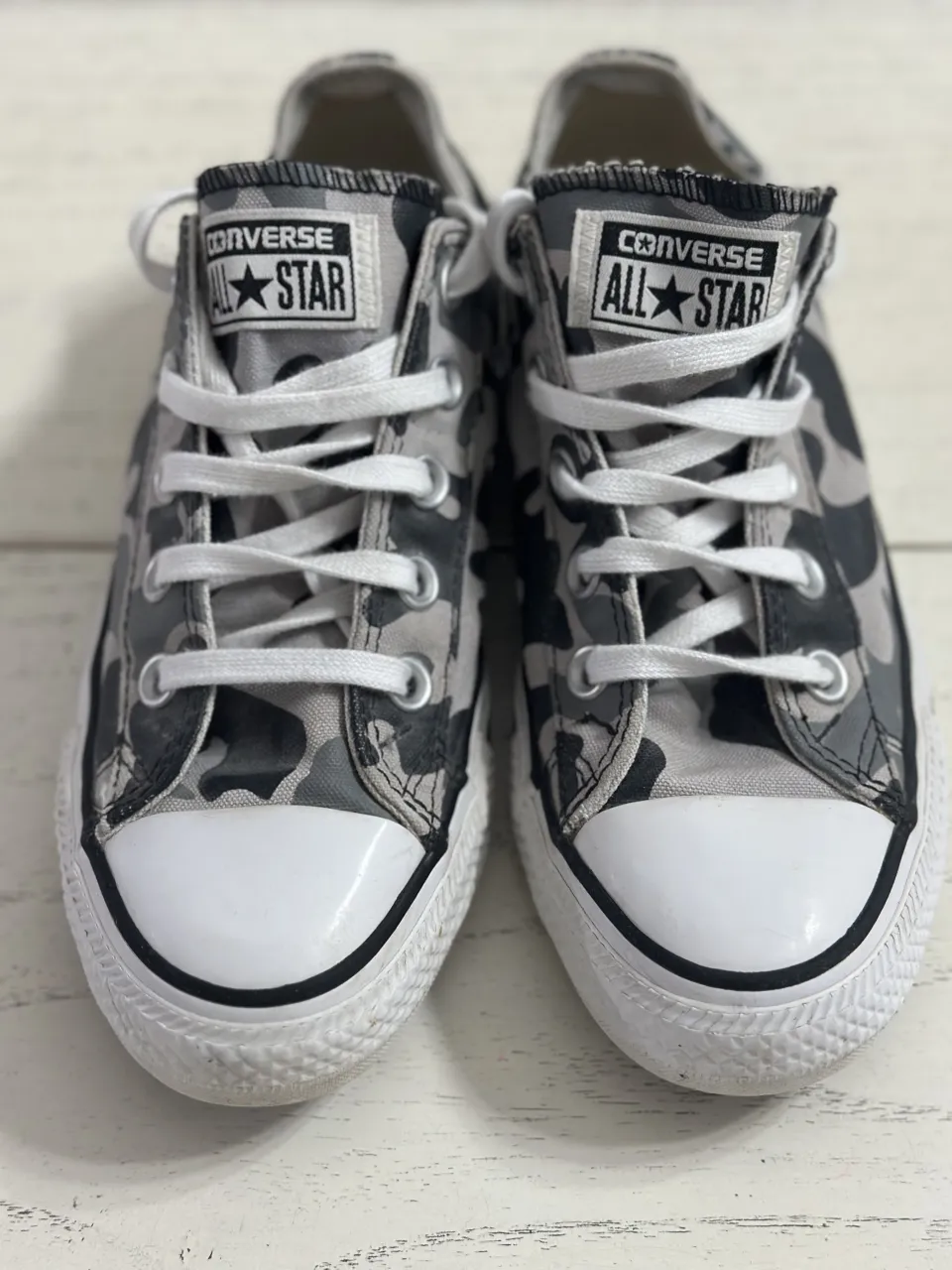 Zapatillas Converse All Star con estampa de camuflaje en tonos grises y negros. Cordones blancos y puntera reforzada.